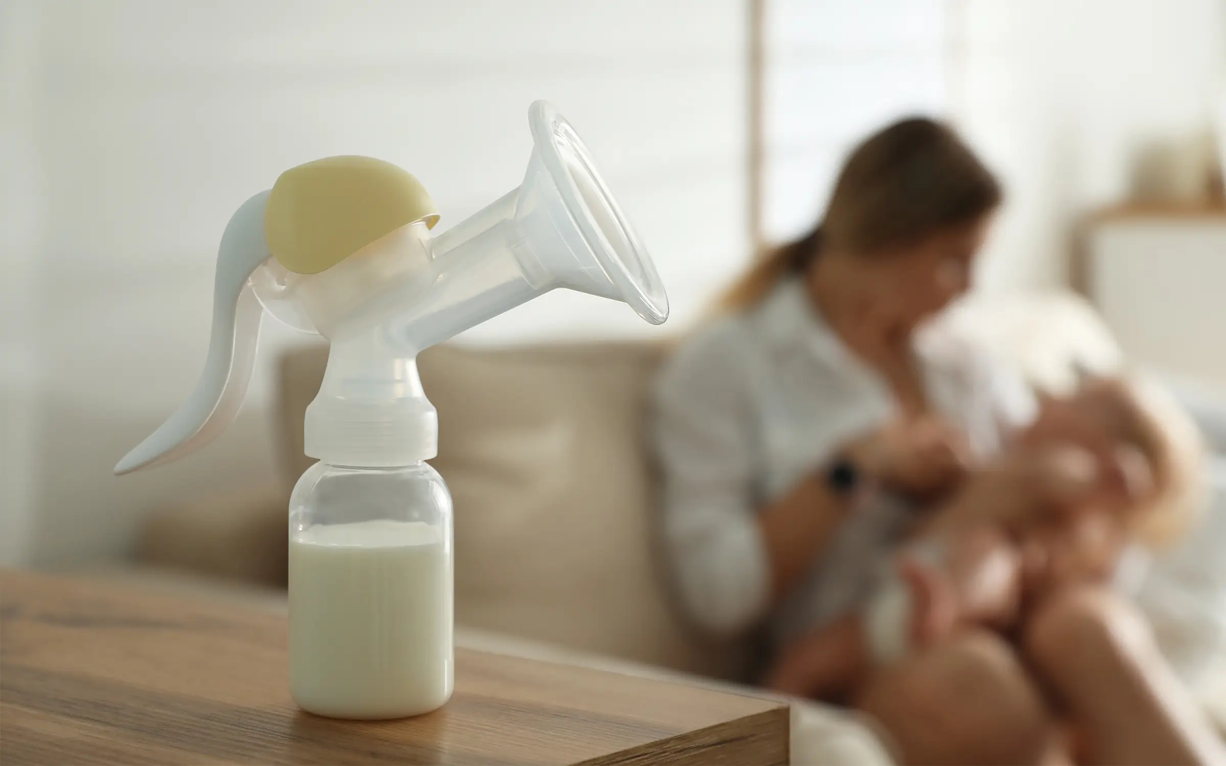 Babyflesje met melk staat op tafel voor een moeder die haar baby verzorgt. 